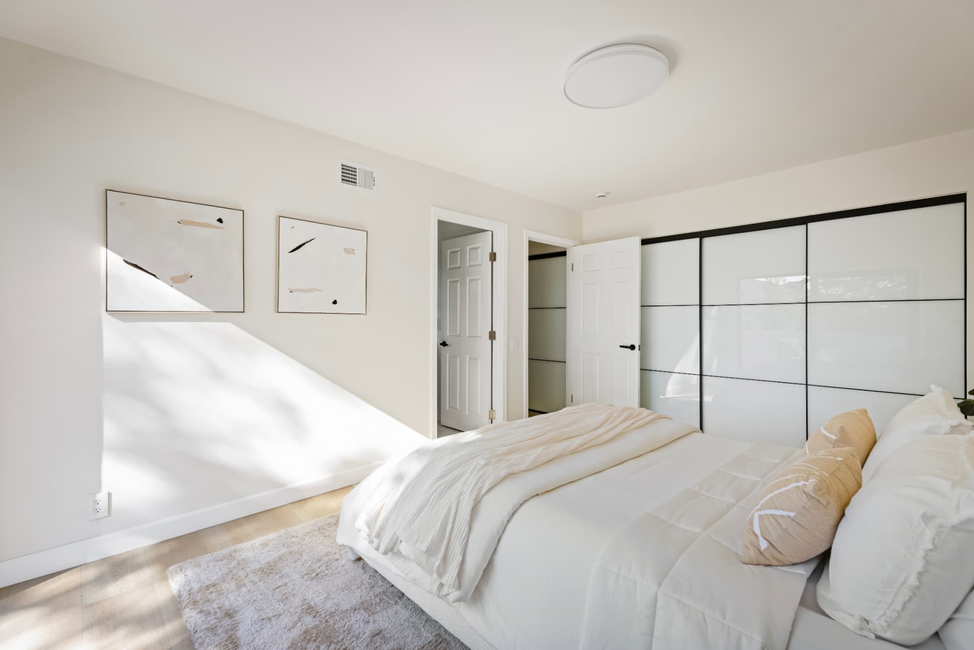 Bedroom with sunlight across the wall and mirrored closets