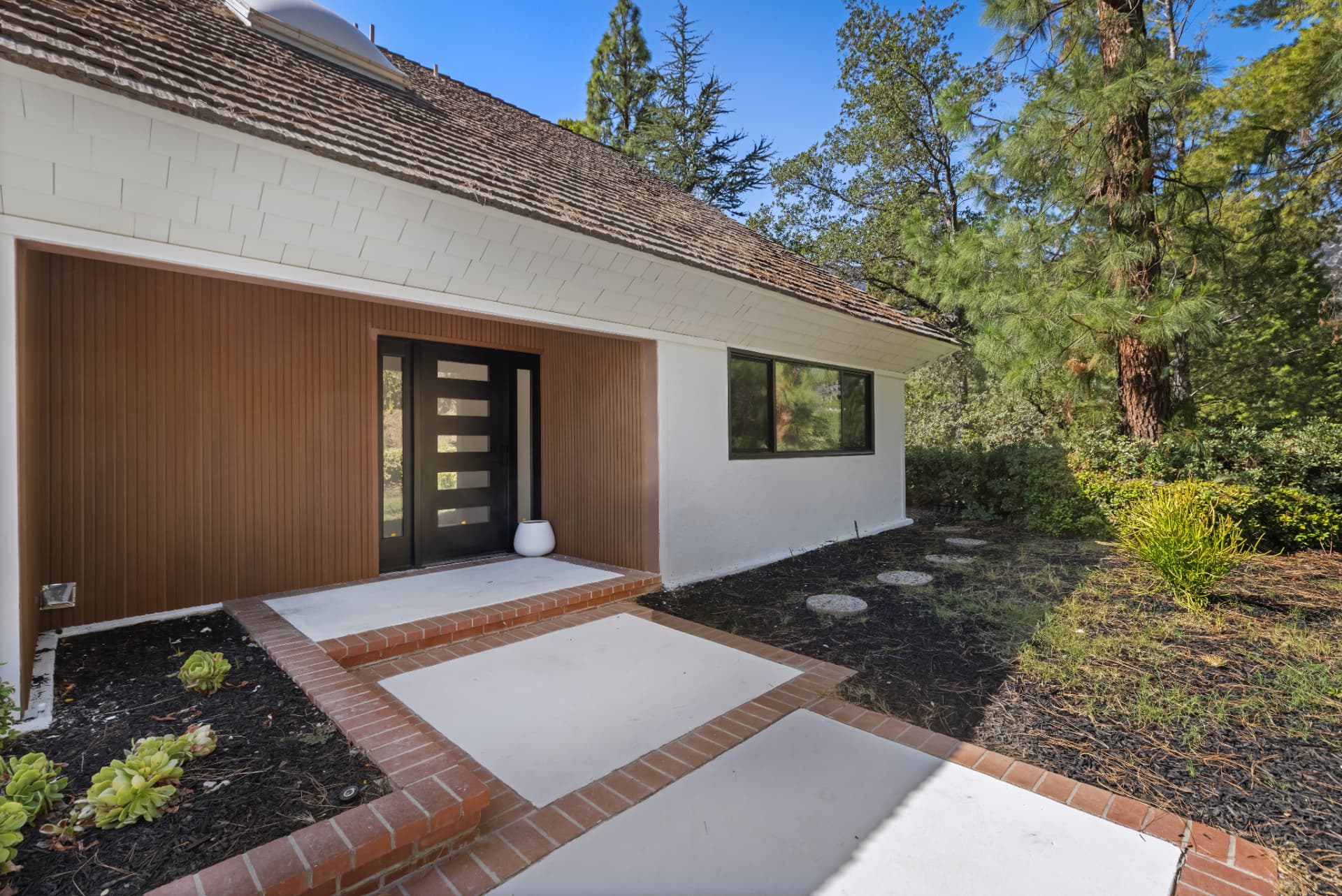Front entry with vertical wood cladding and modern black door