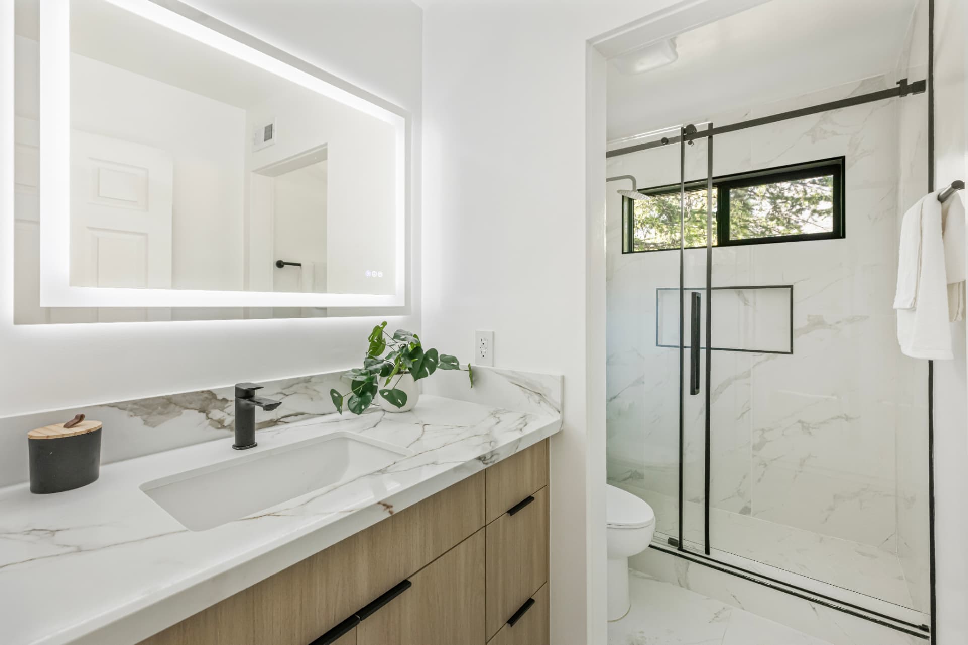 Full bath with backlit mirror and marble-look shower