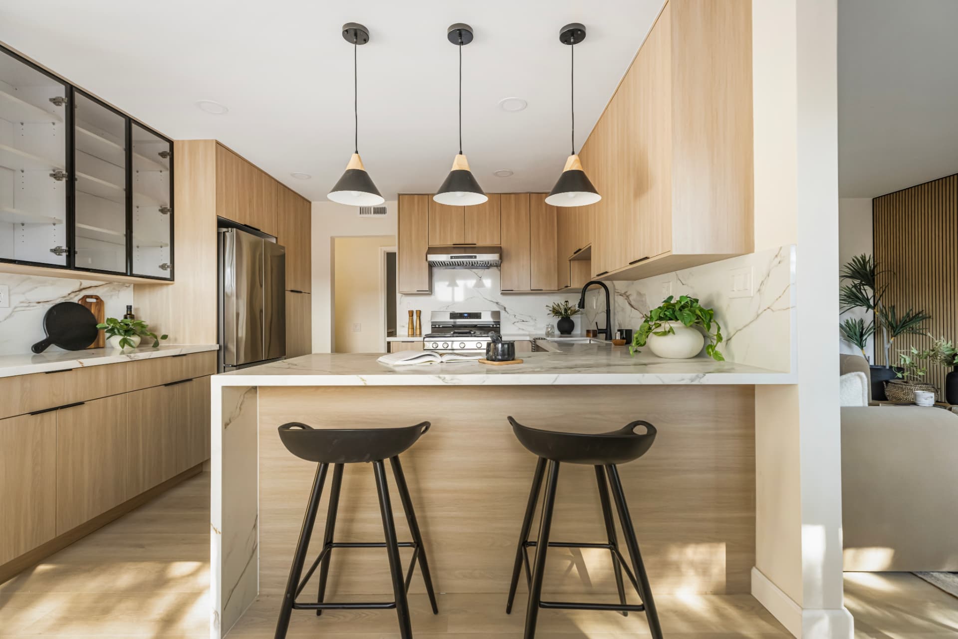 Kitchen with three pendant lights and stone waterfall peninsula